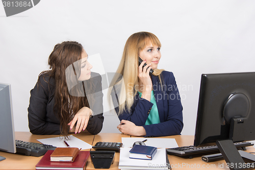 Image of The situation in the office - the employee waits for her colleague, talk on the phone