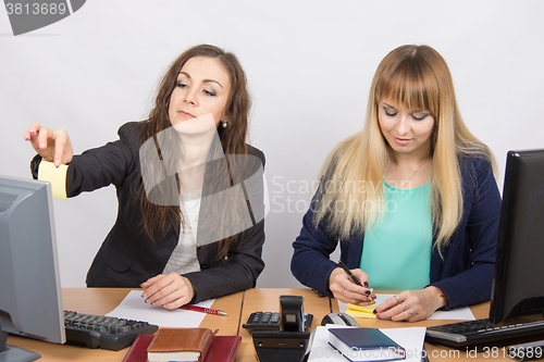 Image of The office staff write reminder notes on a small square