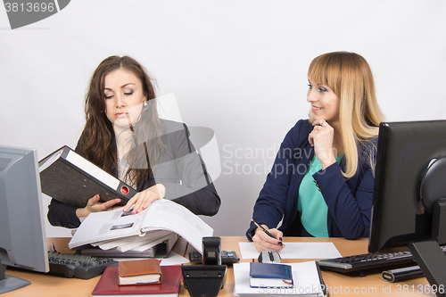 Image of The situation in the office - one employee overburdened, the other does nothing and laughs looking at her