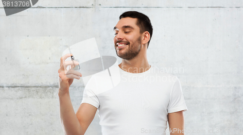 Image of smiling man with male perfume over gray background