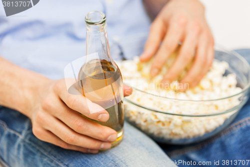 Image of close up of man with popcorn and beer at home