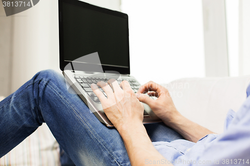 Image of close up of man typing on laptop computer at home