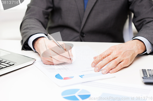 Image of close up of businessman hand with charts in office