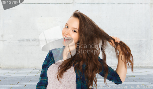 Image of happy teenage girl holding strand of her hair