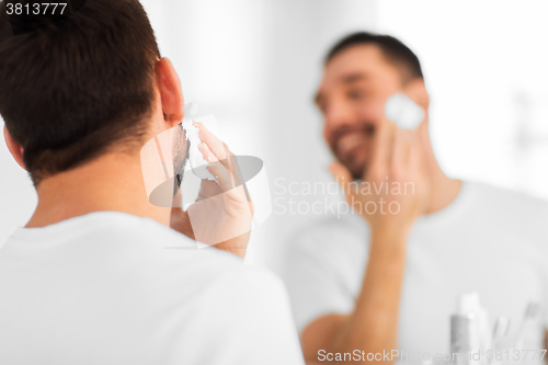 Image of close up of man applying shaving foam to face