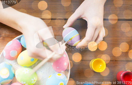 Image of close up of woman hands coloring easter eggs