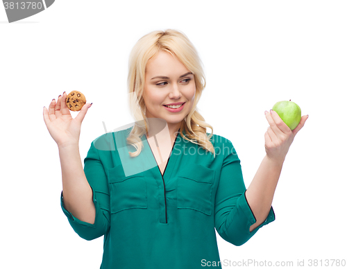 Image of smiling woman choosing between apple and cookie