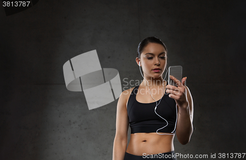Image of woman with smartphone and earphones in gym