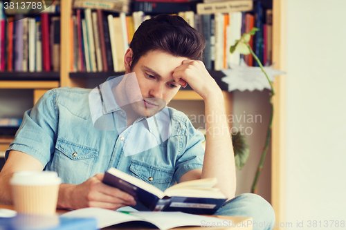 Image of male student reading book in library