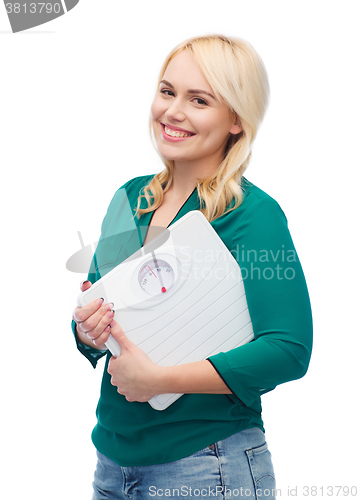 Image of smiling young woman holding scales