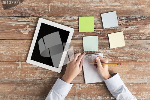 Image of close up of hands with tablet pc and notebook