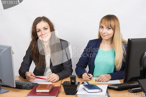 Image of Two business women sitting at a desk in the office desk