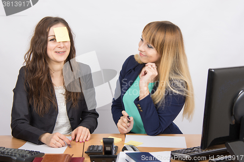 Image of office employee a note taped to the forehead of his colleague