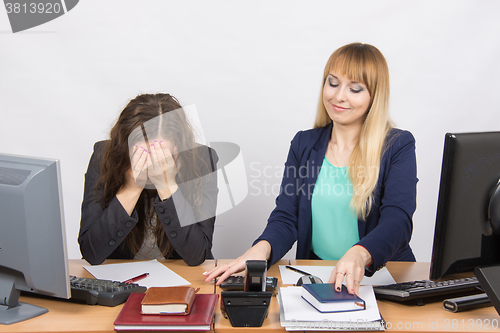 Image of The situation in the office - one girl is very upset, others are pretty straightens things on your desktop