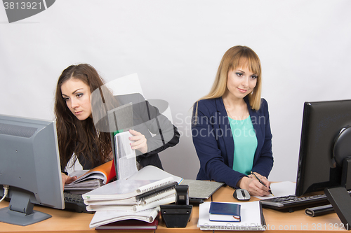 Image of Colleagues in the office Girls, both looking to the first monitor with a bunch of papers and folders, second only to the sheet of paper