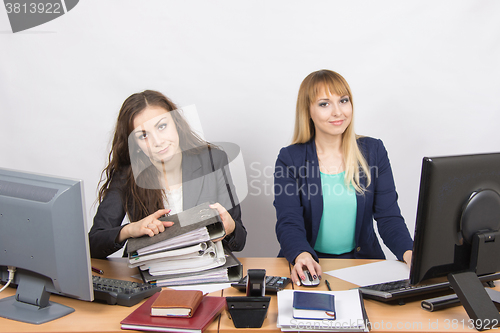 Image of Female colleagues in the office, one littered with paper documents, the second sitting with a blank sheet of paper