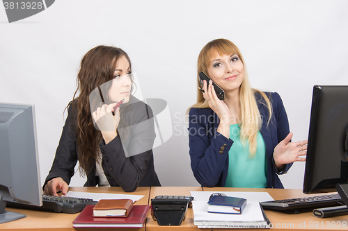 Image of The situation in the office - a girl with a puzzled look on his colleague is talking on the phone