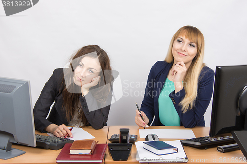Image of The situation in the office - two women dreaming, sitting at a desk