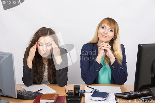 Image of The situation in the office - from one girl really a headache, the other looks happy in the picture