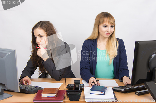 Image of Two office employee working on a computer at the same desk