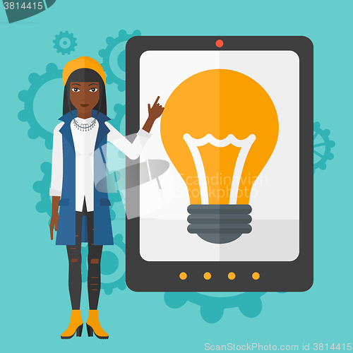 Image of Woman pointing at tablet computer with light bulb on screen.