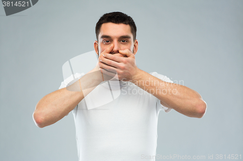 Image of man in white t-shirt covering his mouth with hands