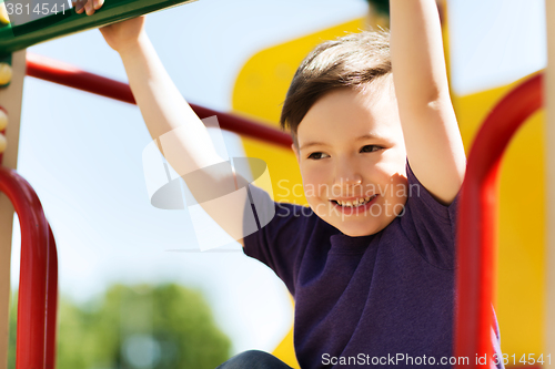 Image of happy little boy climbing on children playground
