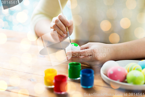 Image of close up of woman hands coloring easter eggs