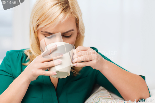 Image of happy woman  with cup of tea or coffee at home
