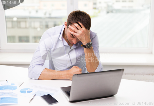 Image of businessman with laptop and papers in office