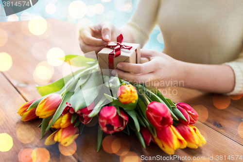 Image of close up of woman with gift box and tulip flowers