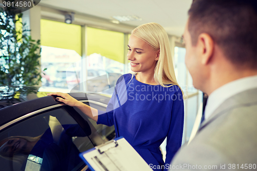 Image of happy woman with car dealer in auto show or salon