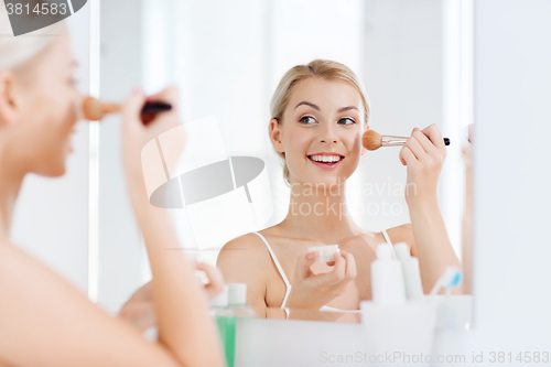 Image of woman with makeup brush and powder at bathroom