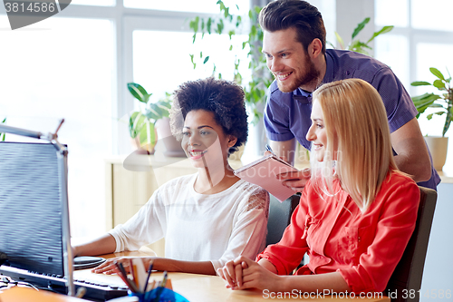 Image of happy creative team with computer in office