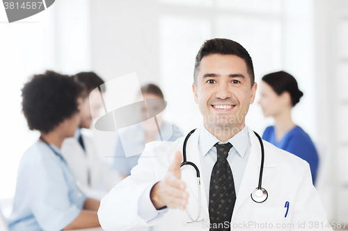 Image of happy doctor over group of medics at hospital