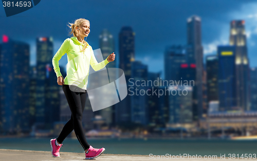 Image of happy woman jogging over city street background