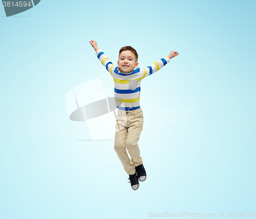 Image of happy little boy jumping in air over blue