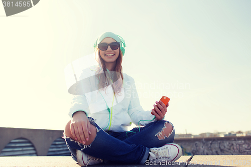 Image of happy young woman with smartphone and headphones