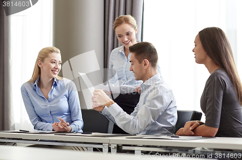 Image of smiling business people with papers in office