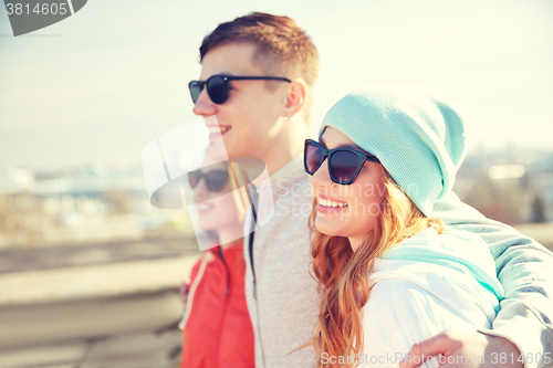 Image of happy teenage friends in shades hugging on street