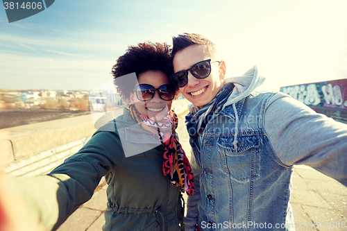 Image of happy teenage couple taking selfie on city street