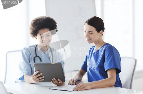 Image of happy doctors with tablet pc meeting at hospital