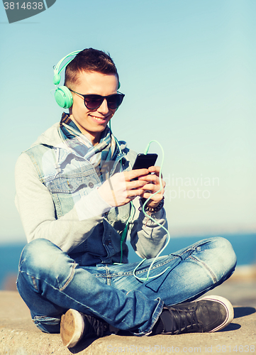 Image of happy young man in headphones with smartphone