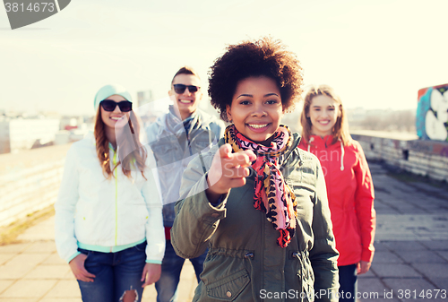 Image of happy friends pointing finger to you on street