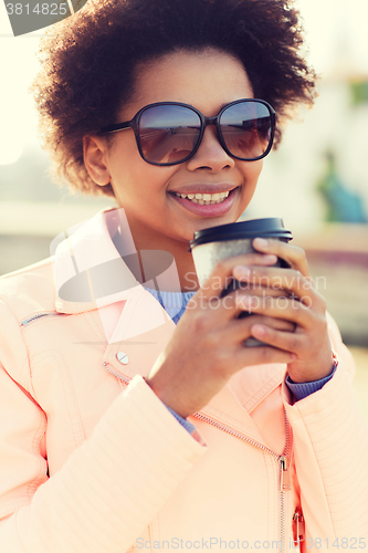 Image of smiling african american woman drinking coffee
