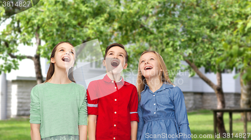 Image of amazed boy and girls looking up over backyard