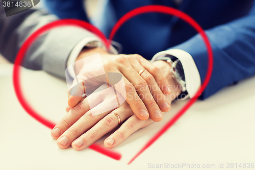 Image of close up of gay couple hands with wedding rings on