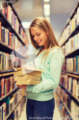 Image of happy student girl or woman with book in library