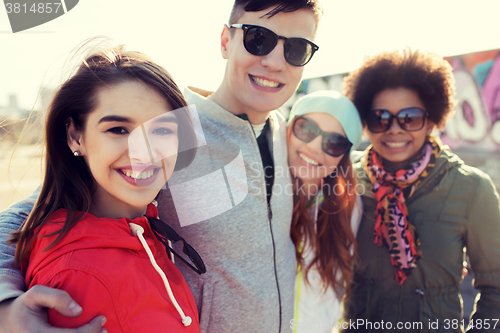 Image of happy teenage friends in shades hugging outdoors