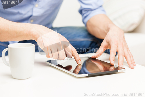 Image of close up of man with tablet pc and tea cup at home